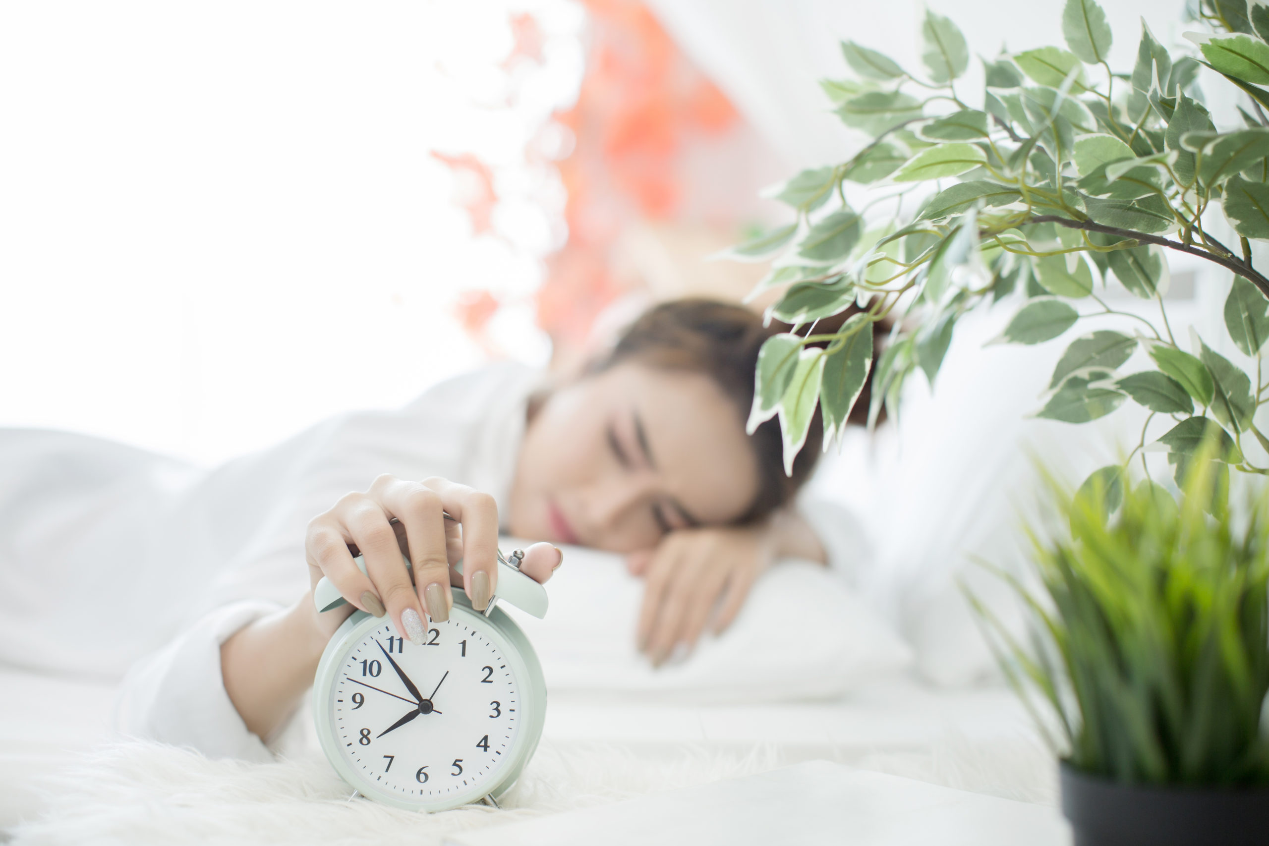 woman asleep in bed while her alarm shows the tim