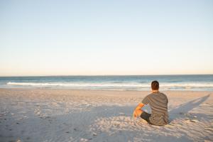 Stress free man relaxing on an empty beach at sunrise